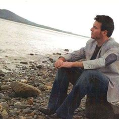 a man sitting on rocks near the water