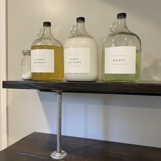 three bottles of liquid sitting on top of a shelf