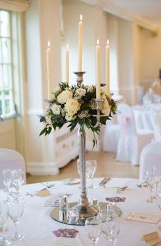 a centerpiece with flowers and candles on a table in a banquet hall or function room