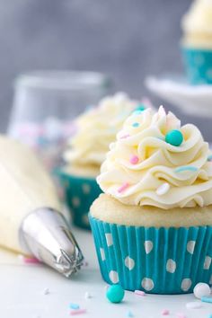 cupcakes with white frosting and sprinkles are on the table