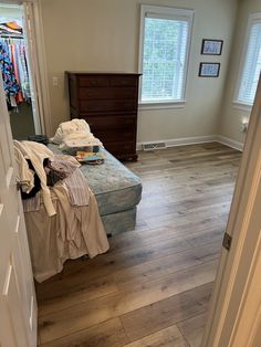 a bed sitting in a bedroom on top of a hard wood floor next to a closet