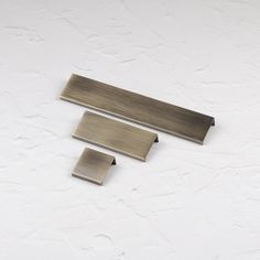 three pieces of metal sitting next to each other on a white surface with no one in it