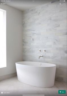 a large white bath tub sitting in a bathroom next to a wall mounted faucet