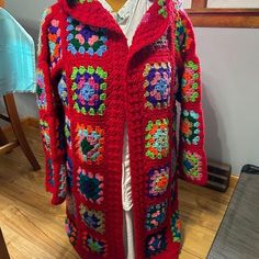 a red crocheted jacket is sitting on a mannequin