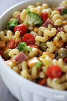 pasta salad with broccoli, tomatoes, and other vegetables in a white bowl