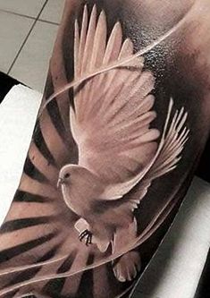 a black and white photo of a dove tattoo on the left upper half of the arm