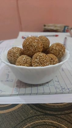 a white bowl filled with oatmeal balls on top of a paper cutting board