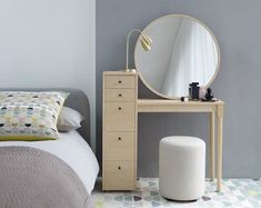 a bedroom with a bed, mirror and stool next to the dresser in front of it