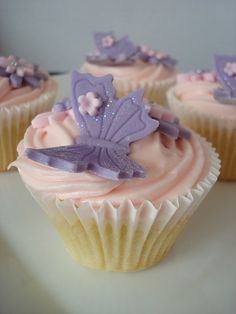 three cupcakes with frosting and purple decorations on them are sitting on a plate