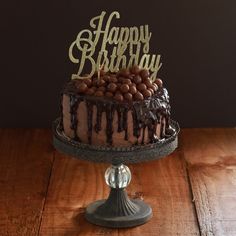 a birthday cake with chocolate frosting and sprinkles sitting on top of a wooden table