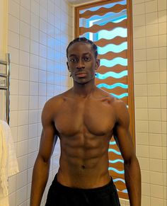 a shirtless man standing in front of a bathroom mirror next to a towel rack