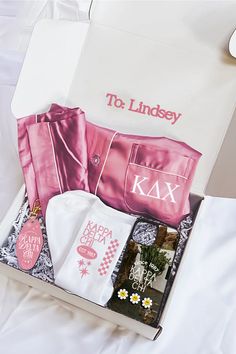 an open box containing clothing and personal items on a white bed with the name kax printed on it