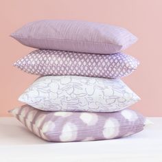 four pillows stacked on top of each other in front of a pink wall and floor