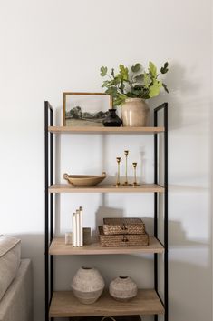 a shelf with vases, books and other items on it in a living room