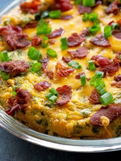 an omelet with bacon and green onions in a metal pan on a table