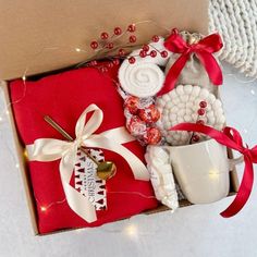 a red box with white and red items in it on top of a table next to a cup