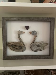 two ducks made out of driftwood in a shadow box with hearts on the wall