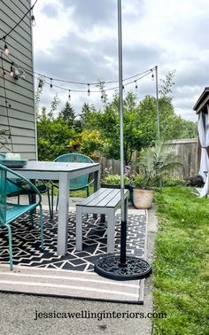 an outdoor table and chairs on a patio with lights strung over the back yard area