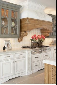 a kitchen with white cabinets and flowers on the stove top, in front of an oven