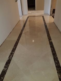 an empty hallway with white walls and marble flooring on one side, and black lines on the other