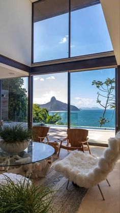 a living room filled with furniture next to a large glass window overlooking the ocean and mountains