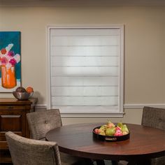 a dining room table with chairs and fruit bowl on the table in front of it