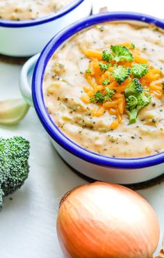 two bowls filled with soup and broccoli next to an onion