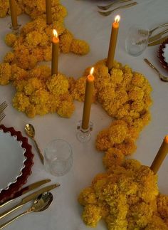 the table is set with yellow flowers and candles