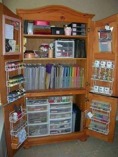 an open cabinet with lots of crafting supplies in the bottom section and shelves on both sides