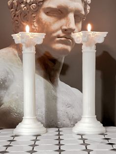 two white candles sitting on top of a table next to a bust of abraham lincoln