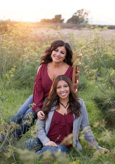 two women sitting in tall grass smiling at the camera