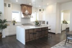 a kitchen with white cabinets and wood flooring next to a plant in a pot