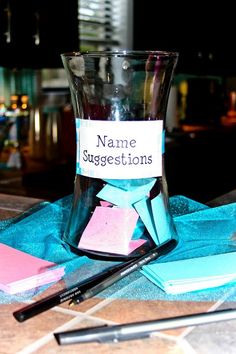 a glass with some writing on it sitting next to a pen and notebooks that have been placed in front of them