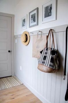 two hats hanging on the wall next to a purse and hat rack in a hallway