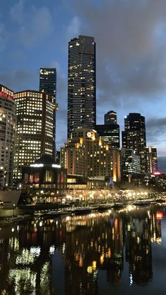 the city is lit up at night and reflecting in the water