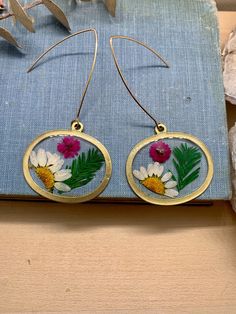 "This unique pair of earrings features wildflowers, forever stored in UV resistant resin. They hang from gold hooks that are hypoallergenic. . . . . . . . . \"...I don't really want to be witnessed talking to the catbirds or hugging the old black oak tree... Besides, when I am alone I can become invisible. I can sit on the top of a dune as motionless as an uprise of weeds, until the foxes run by unconcerned. I can hear the almost unhearable sound of the roses singing. If you have ever gone to th Black Oak Tree, Gold Hooks, Earrings Resin, Resin Earrings, Oak Tree, Earrings Jewelry, Earring Gifts, Gift For Mom, Wild Flowers