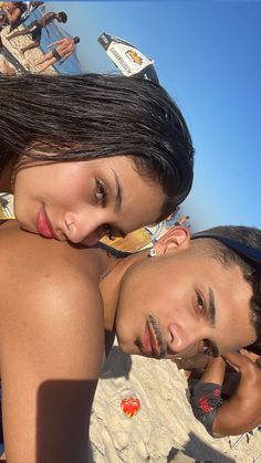 a man and woman laying on the beach next to each other with their heads together