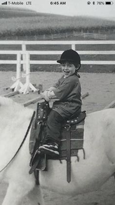 a young boy riding on the back of a white horse