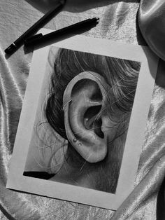 a black and white photo of a woman's ear with a pencil drawing on it