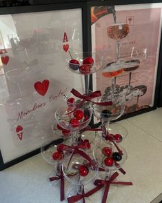 wine glasses with cherries in them are stacked on top of each other near a framed poster