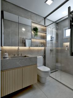 a bathroom with a toilet, sink and shower stall in the middle of it is illuminated by recessed lights