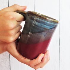 a person holding a coffee cup in their hand on a white wooden background with planks