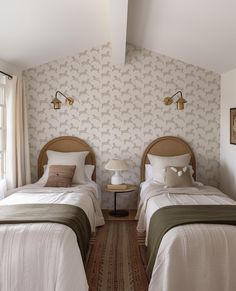 two twin beds in a bedroom with wallpaper and lamps on either side of them