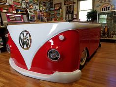 a red and white vw bus sitting on top of a hard wood floor in a store