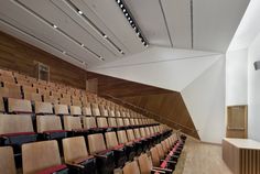 an empty auditorium with rows of chairs and a podium on the side, in front of a white wall