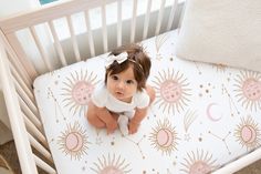 a baby sitting in a crib next to a pillow