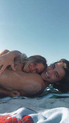 two beautiful women laying on top of a beach next to each other