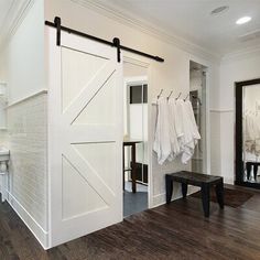 a white bathroom with wooden floors and sliding barn doors on the wall, next to a sink