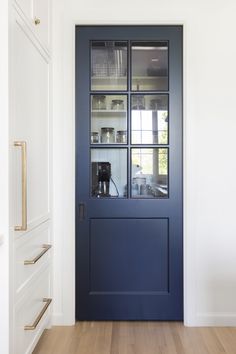 a blue front door with glass inserts on the side and shelves above it in an otherwise white room