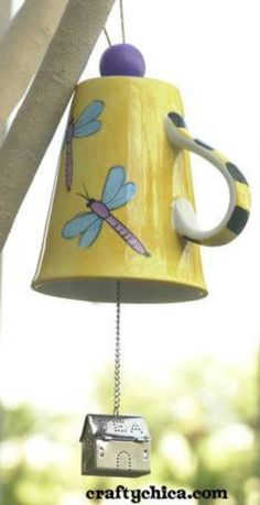 a yellow birdhouse with dragonflies on it's side hanging from a tree